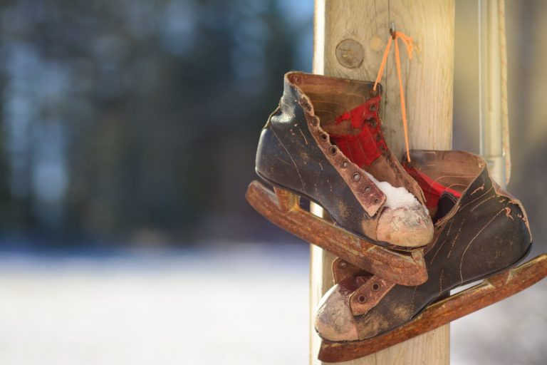 pair of black-and-brown ice skates hanging on brown wooden post